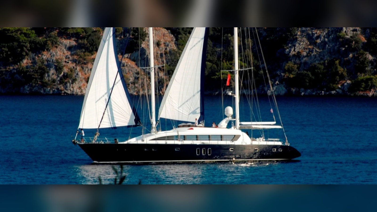 Beluga under sail off a rocky coast