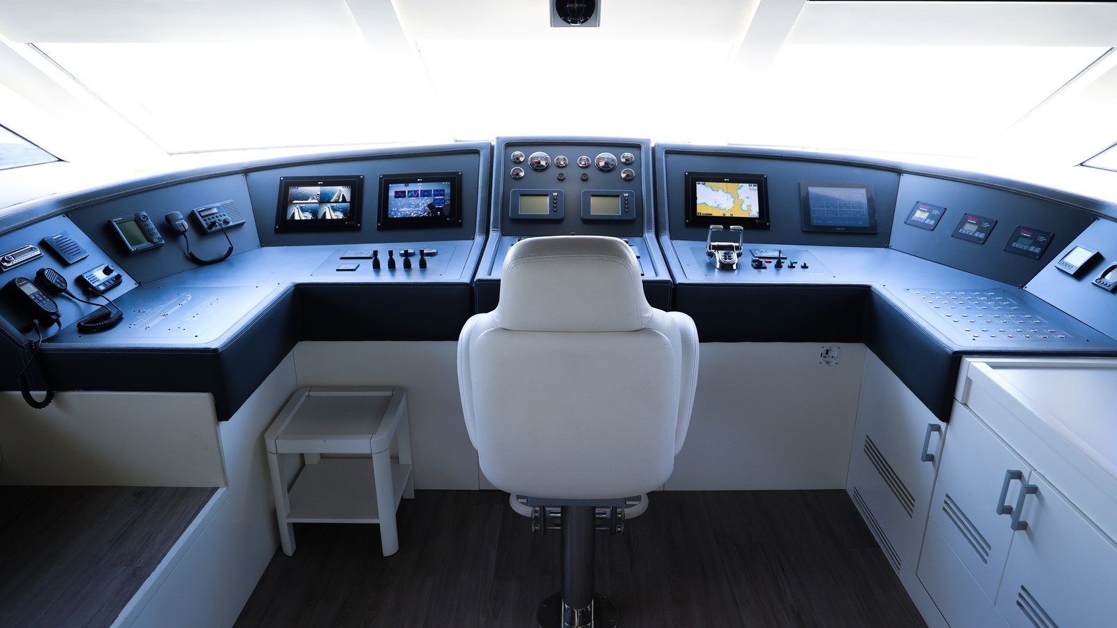 A finished yacht wheelhouse with the chart and radar screens, engine controls and communications sets in place and the helm chair empty