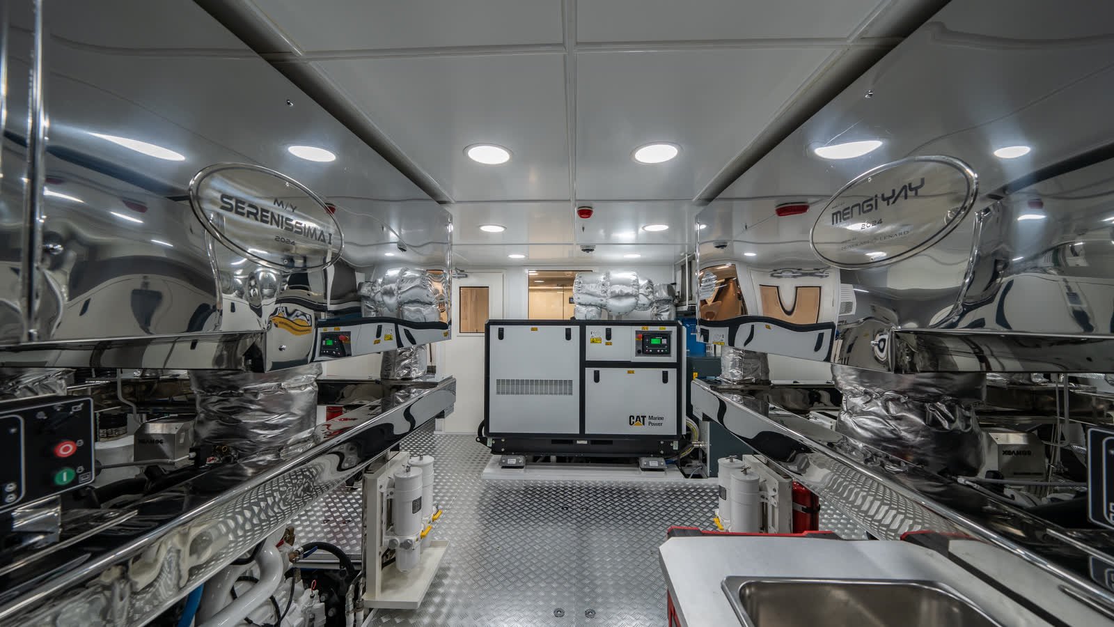 A yacht machinery and service space with stainless worktops, diamond-plate decking and a generator set standing between the units