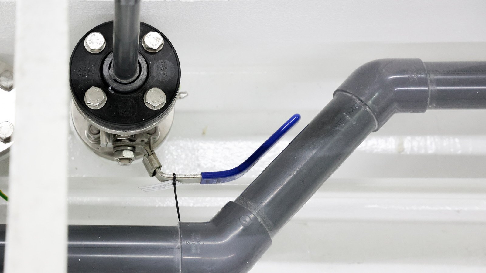 A shaft penetration bolted through the tank top of a machinery space, its flange studded and made up, with a grey pipe run and a blue handled valve alongside