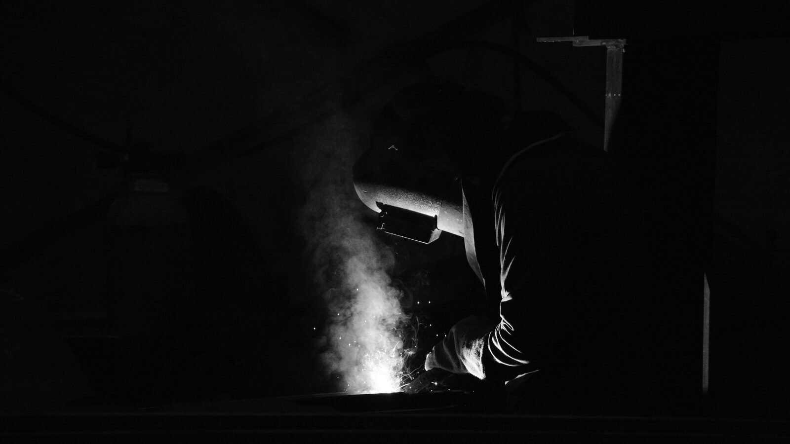 A welder at the arc in the Tuzla yard, the weld zone the only light in the frame